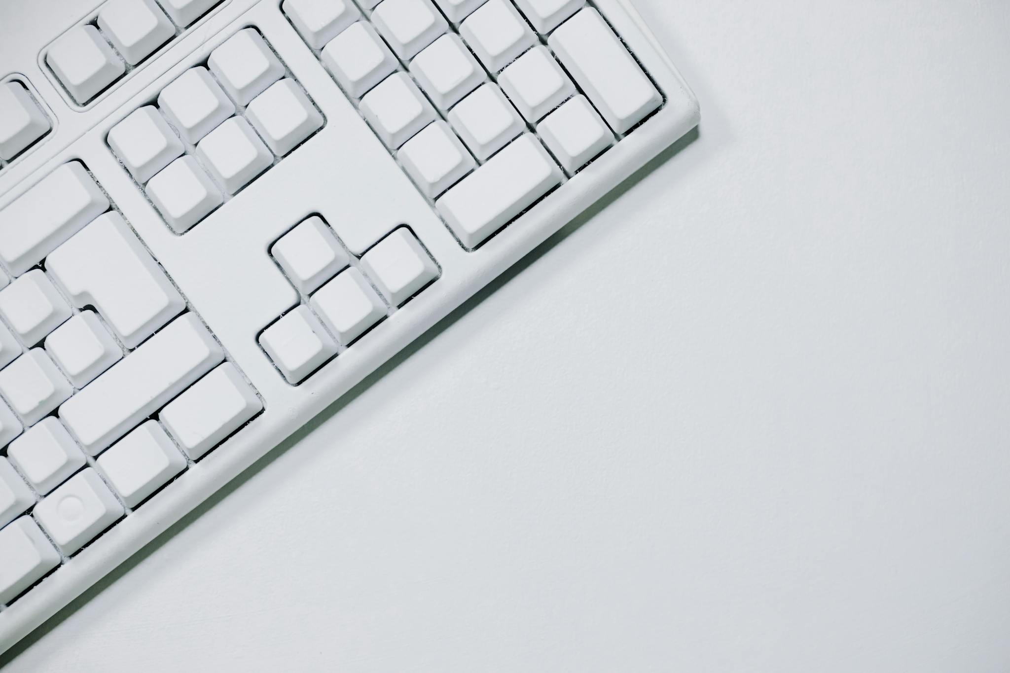 A minimalist white keyboard in a flat lay on a white background, ideal for tech-related content.