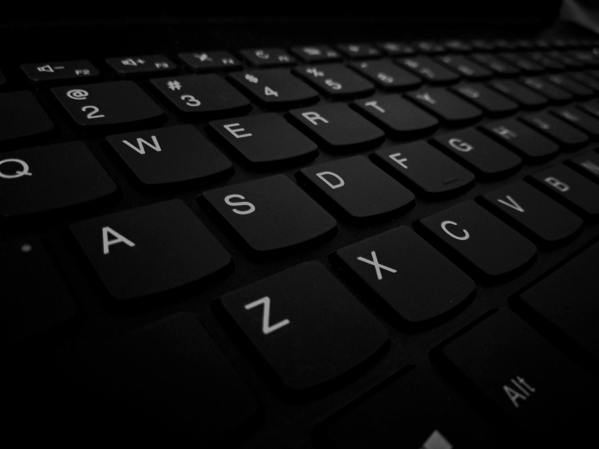 Dramatic close-up of a black computer keyboard showing detail of keys.