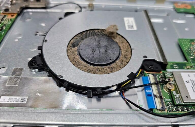Ventilateur de refroidissement de PC portable couvert de poussière, pales et grille obstruées