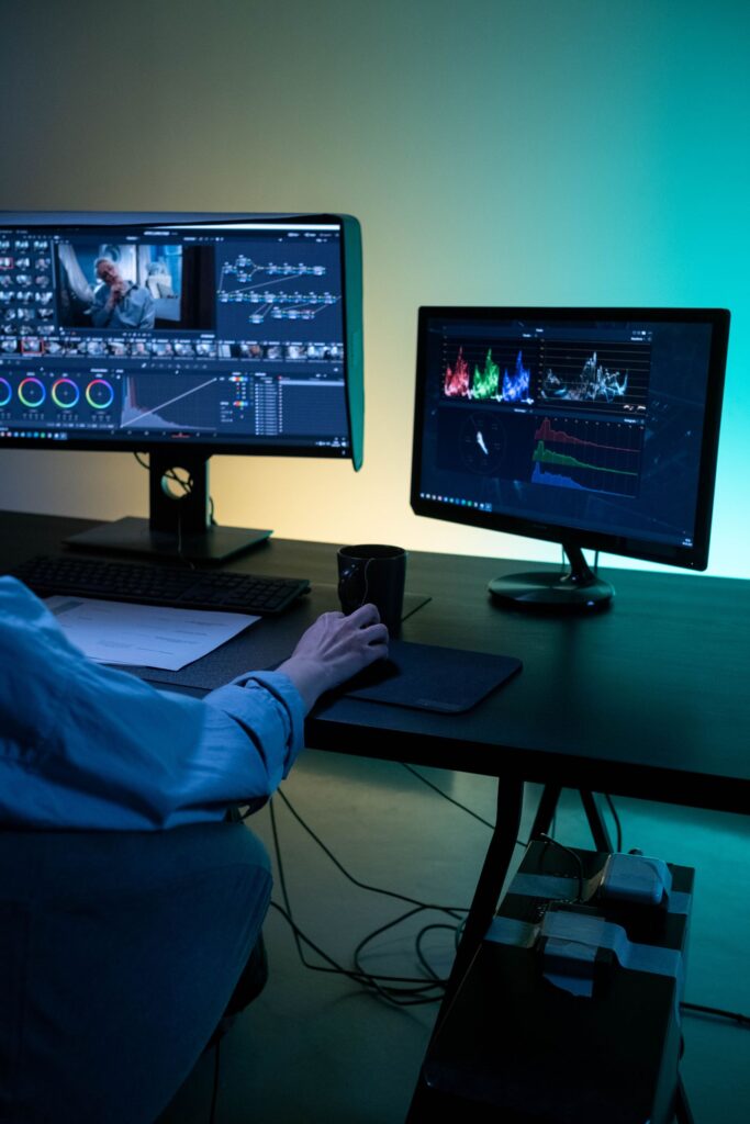 Utilisateur devant deux écrans de PC sous Windows, clavier et souris sur un bureau sombre