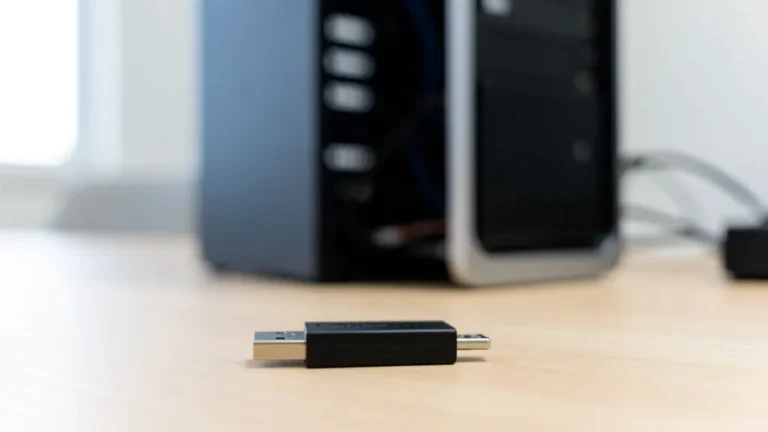 Clé USB noire posée sur un bureau clair devant une tour de PC de bureau Windows